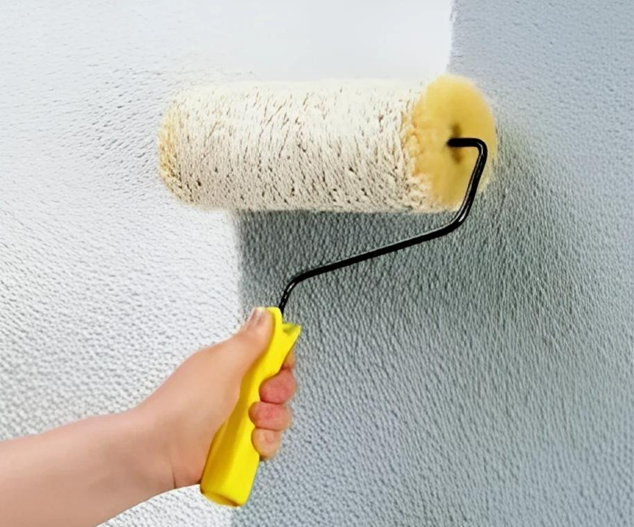 Malování zdi rukou s profesionálním stříkacím přístrojem